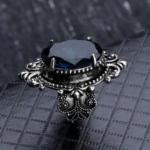 Dettaglio dell'anello gotico retrò con pietra blu ovale e intricate incisioni in argento