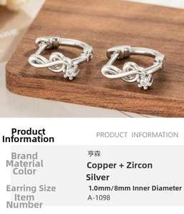 Detailed view of silver musical note huggie earrings with cubic zirconia inlay