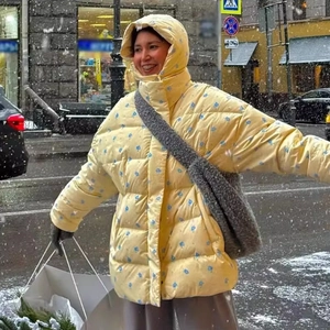 Women's yellow floral hooded winter puffer jacket in a snowy street scene