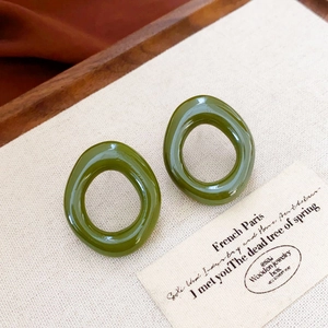 Detail of minimalist olive green resin earrings with an irregular geometric hollow shape