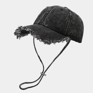 Détail d'une casquette en denim délavé avec bords usés et cordon coupe-vent réglable