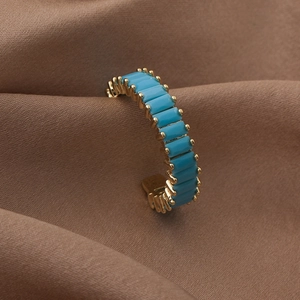 Detail of adjustable gold ring featuring vibrant blue square zirconia on silk fabric
