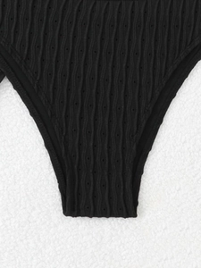 Detailed close-up of black bikini bottoms with wave texture and pointelle hollow design