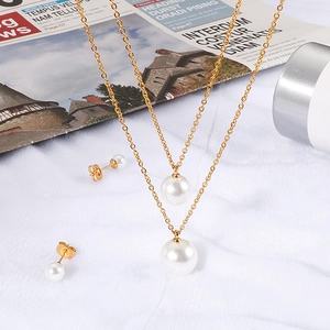 Elegant gold double-layered necklace and round pearl stud earrings set on white fabric