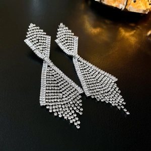 Close-up of silver tassel earrings with shimmering rhinestones on a black background