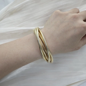 Detail shot of multi-layer gold snake bone wrap bracelet worn on a female wrist