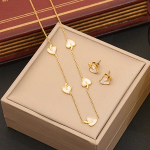 Détail d'un ensemble collier et boucles d'oreilles cœur doré avec nacre blanche