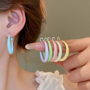 Macro view of C-shaped candy color hoop earrings in vibrant pastel lacquer finishes