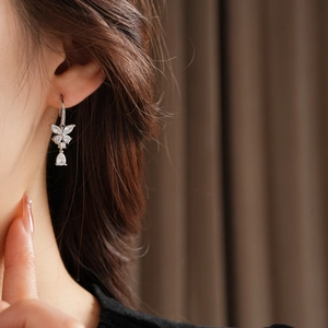 Gros plan d'une boucle d'oreille papillon en argent avec zircons portée par un modèle