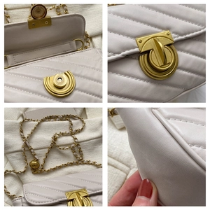 Detail view of cream quilted crossbody bag featuring gold T-bar lock and chain strap