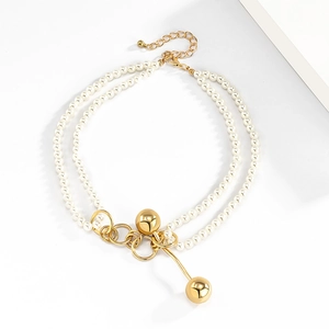 Detail of double-layer faux pearl necklace with gold interlocking rings and bead charms