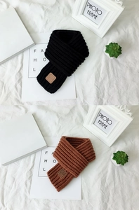 Detail of knitted winter scarves in black and brown featuring a leather LOVE patch