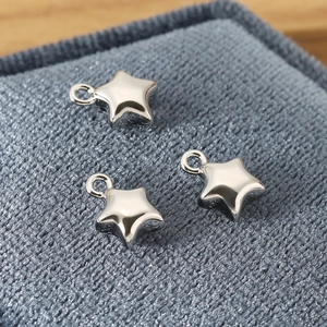 Macro detail of three polished silver star-shaped metal pendants on textured fabric
