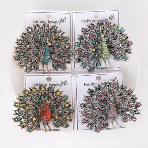 Detailed view of four peacock brooches with colorful rhinestones on a white plate
