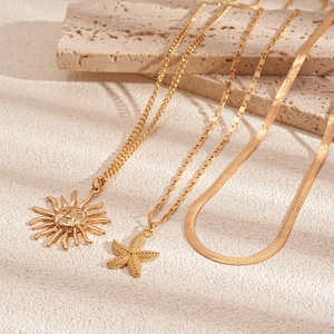 Detailed view of 3-piece gold sun face and starfish charms with snake chain necklaces