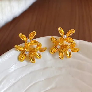 French vintage gold flower earrings with pearls on a white ceramic tray over wood