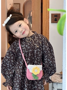 Detail of child wearing a pink hand-crocheted shoulder bag with white flower decoration