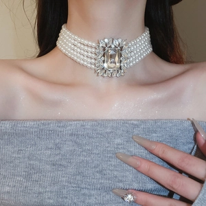 Detail of multi-layer pearl necklace with square crystal pendant worn on the neck