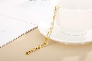 Detail of gold double-layer snake chain bracelet with white pearl flower on a cup