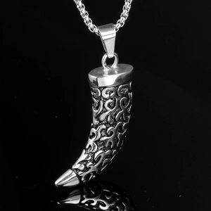 Macro shot of silver crescent pendant with totem engravings and metal chain necklace