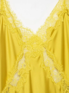 Détail d'une robe en satin jaune vif avec des finitions délicates en dentelle au décolleté