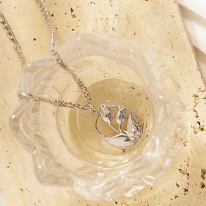 French vintage silver tulip pendant necklace with cutout floral design on stone background