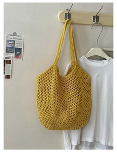 Close-up of yellow hand-woven cotton thread mesh bag hanging on a wooden wall hook