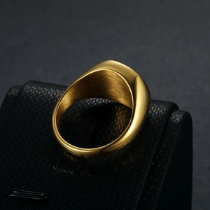 Detailed close-up of a polished gold-plated signet ring with a smooth finish and brushed interior