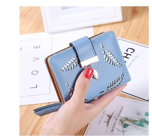 Detail of light blue PU leather wallet featuring hollow leaf pattern and gold charm
