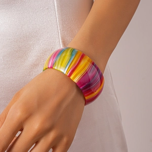 Gros plan d'un bracelet jonc géométrique en acétate à rayures colorées sur le poignet