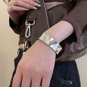 Détail d'un large bracelet manchette en argent poli au poignet pour un style minimal
