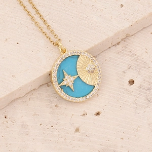Macro view of gold pendant with turquoise, zircon accents and star shell engraving