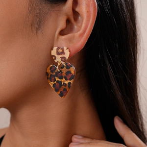 Close-up of leopard print heart earrings on model showing retro acrylic texture and design