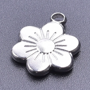 Macro shot of a silver five-petal flower pendant in stainless steel with inner floral texture