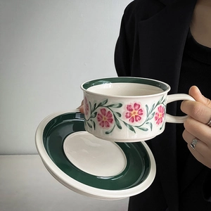 Detailed close-up of hand-painted pink floral patterns on a vintage ceramic coffee cup set