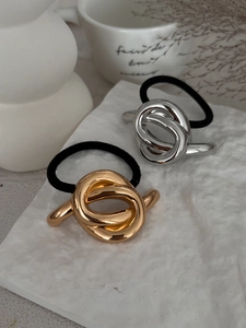 Detailed view of elegant gold and silver metallic knot hair ties on a textured background