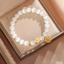 Macro view of cat-eye beads bracelet with golden flower charm and fortune pendant