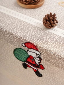 Close-up of Santa Claus embroidery on festive beige table runner with rustic pine cones