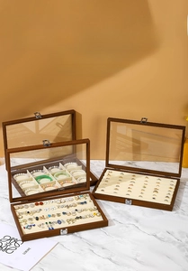Detail view of walnut wood jewelry boxes with glass lids and soft beige velvet interior