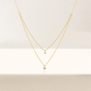 Detail of a double-layered 925 silver necklace with sparkling clover and diamond pendants