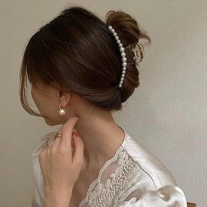 Detailed close-up showing a large pearl hair claw clip worn on a woman's long hair