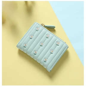 Close-up of mint green folded wallet with vertical quilting and small white flower embroidery