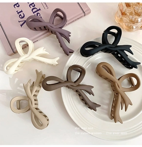 Detailed view of six matte bow claw clips in earthy colors on decorative setting