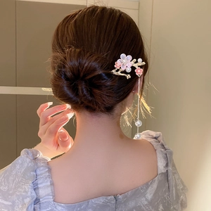Détail de l'épingle à cheveux muguet avec pétales roses et glands de perles sur chignon
