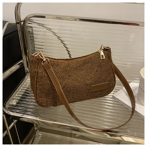 Detailed view of the brown woven texture and leather strap on a vintage underarm bag