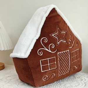 Close-up of gingerbread house plush pillow with festive embroidery and soft texture