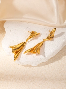 Detail view of gold lava teardrop earrings on white stone with silk background