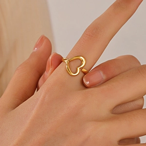 Golden heart-shaped open adjustable ring shown on a model hand with sharp metal reflections