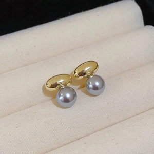Gros plan détaillé de boucles d'oreilles en perles grises avec clous dorés sur un écrin