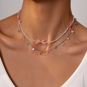 Close-up of layered beaded necklace featuring a pink bow and colorful zircon drops